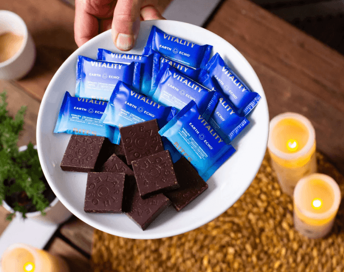 A person holding a plate with Earth Eco Vitality  Bite chocolate bars on it.