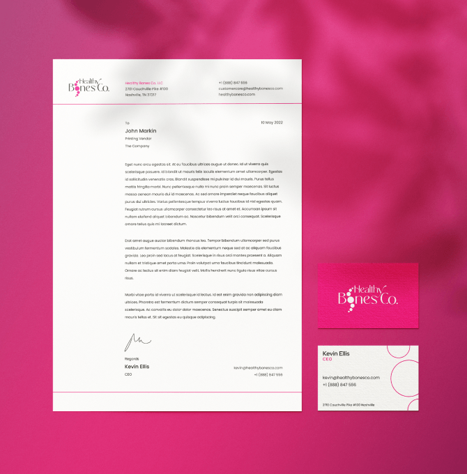 A pink business card and letterhead displayed against a matching pink background, showcasing a cohesive design.