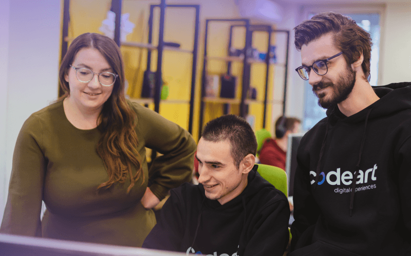 Three people gathered around a computer screen, engaged in focused discussion