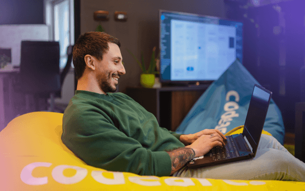 A man sitting on a bean bag chair with a laptop, working comfortably